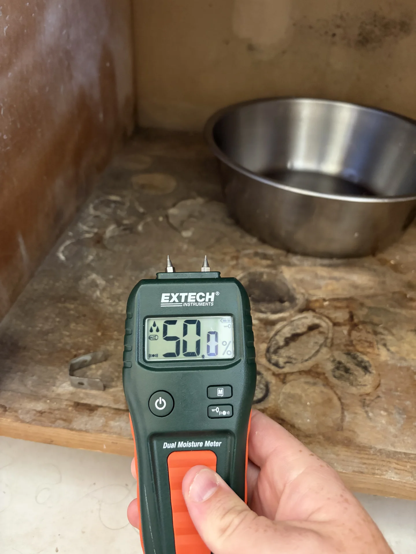 Comparative moisture reading of 50.0 on water-damaged bathroom cabinet floor