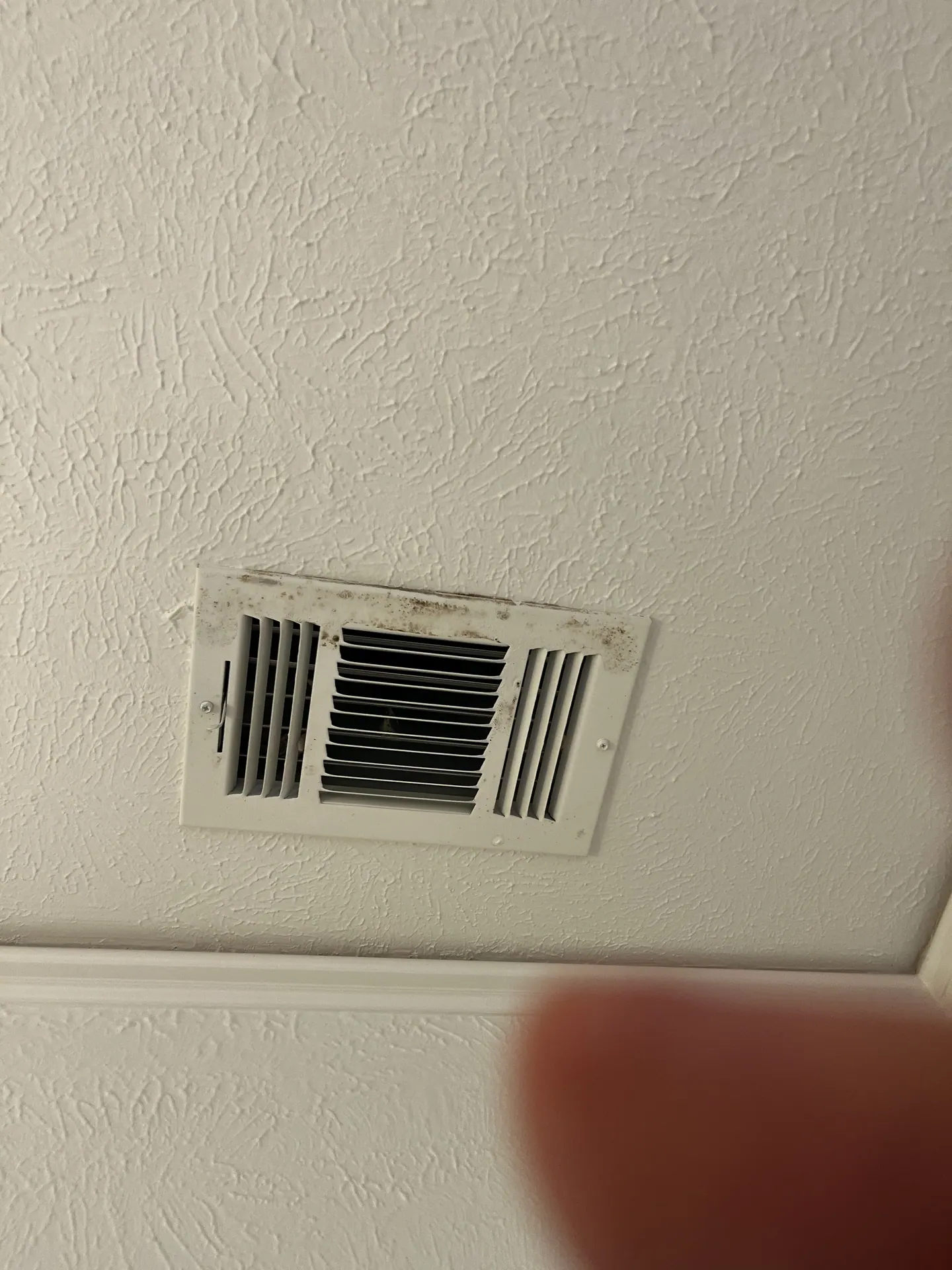Localized discoloration on a bathroom HVAC supply grill whose duct behind it appeared clean
