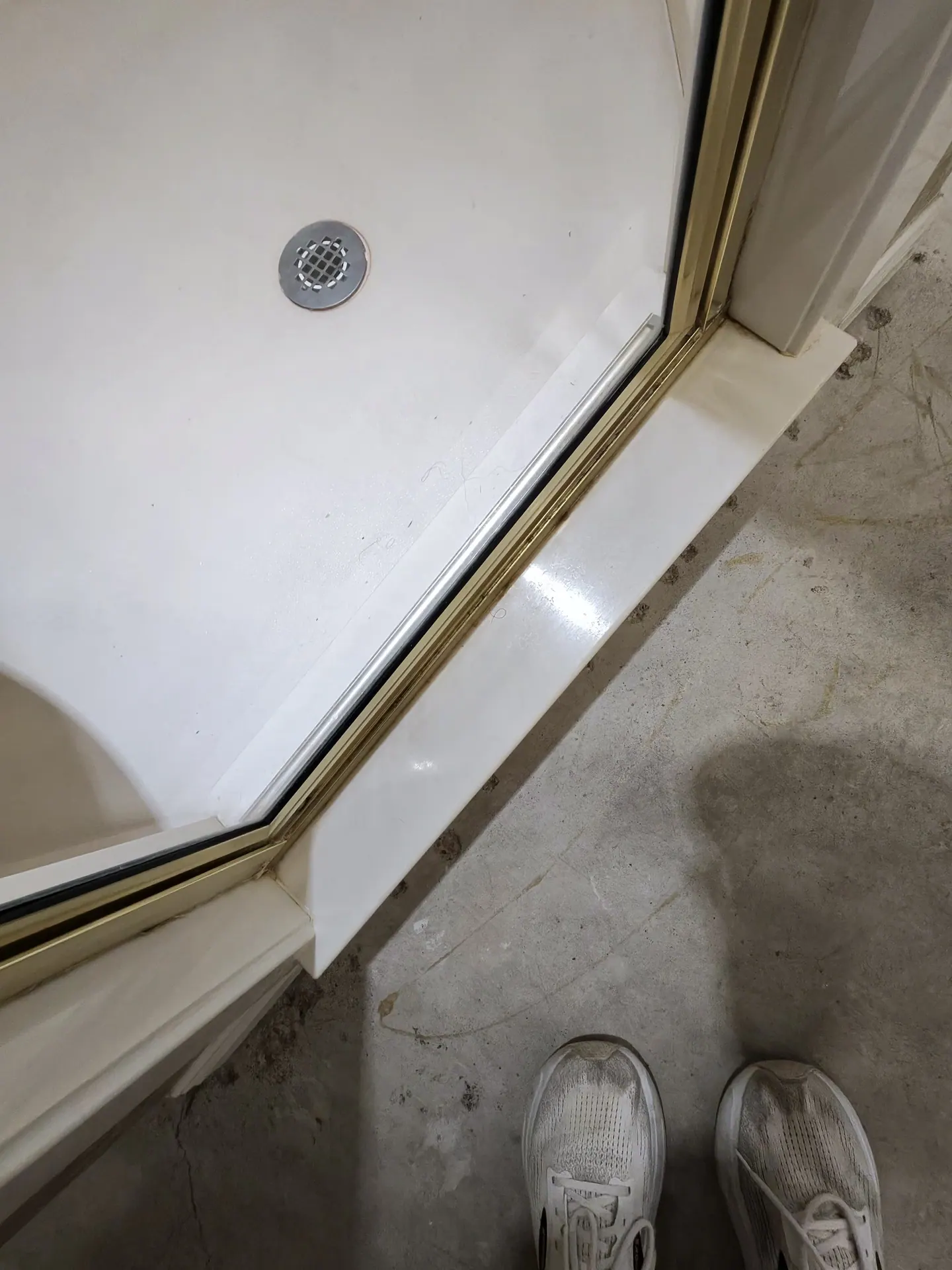 Discoloration on the floor beside a shower curb that returned No Mold Detected on a surface swab