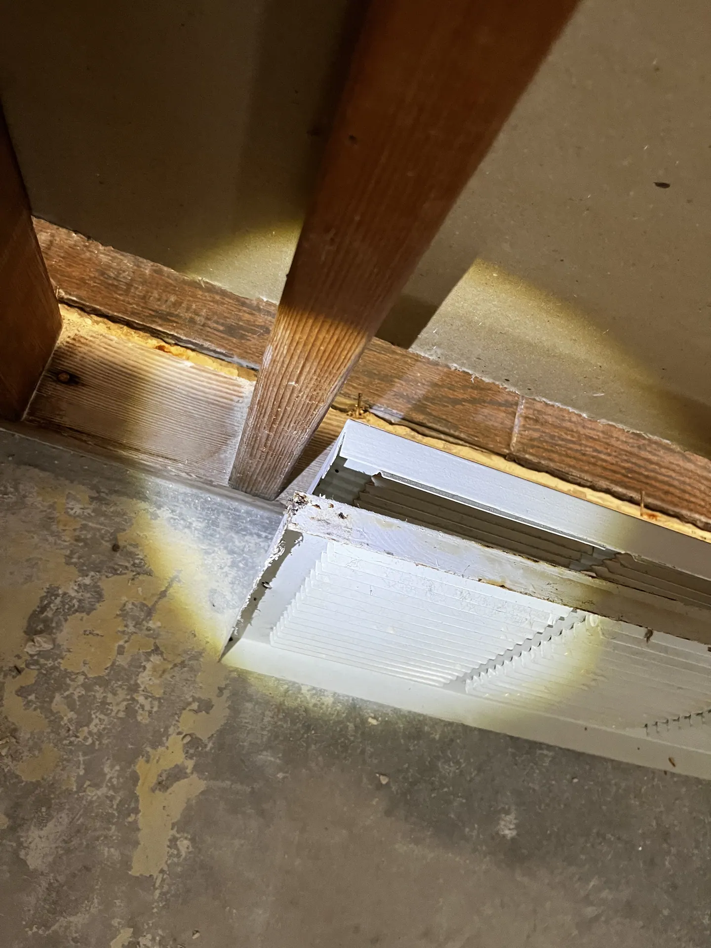 Exposed framing, concrete floor and an HVAC grille after flood-cut work in a water-affected Fort Worth home