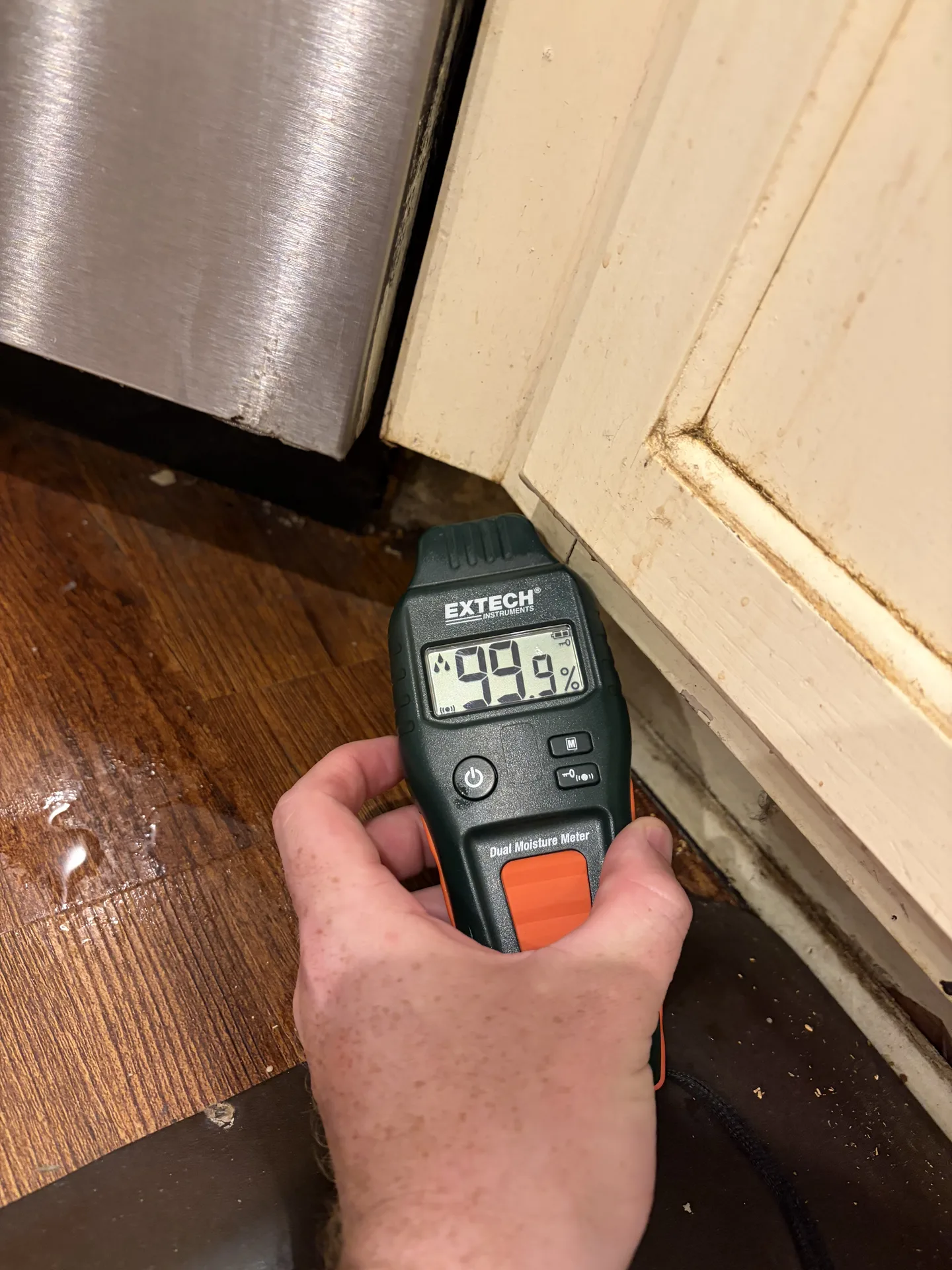 Wet cabinet toe-kick beside leaking dishwasher with maximum comparative moisture reading