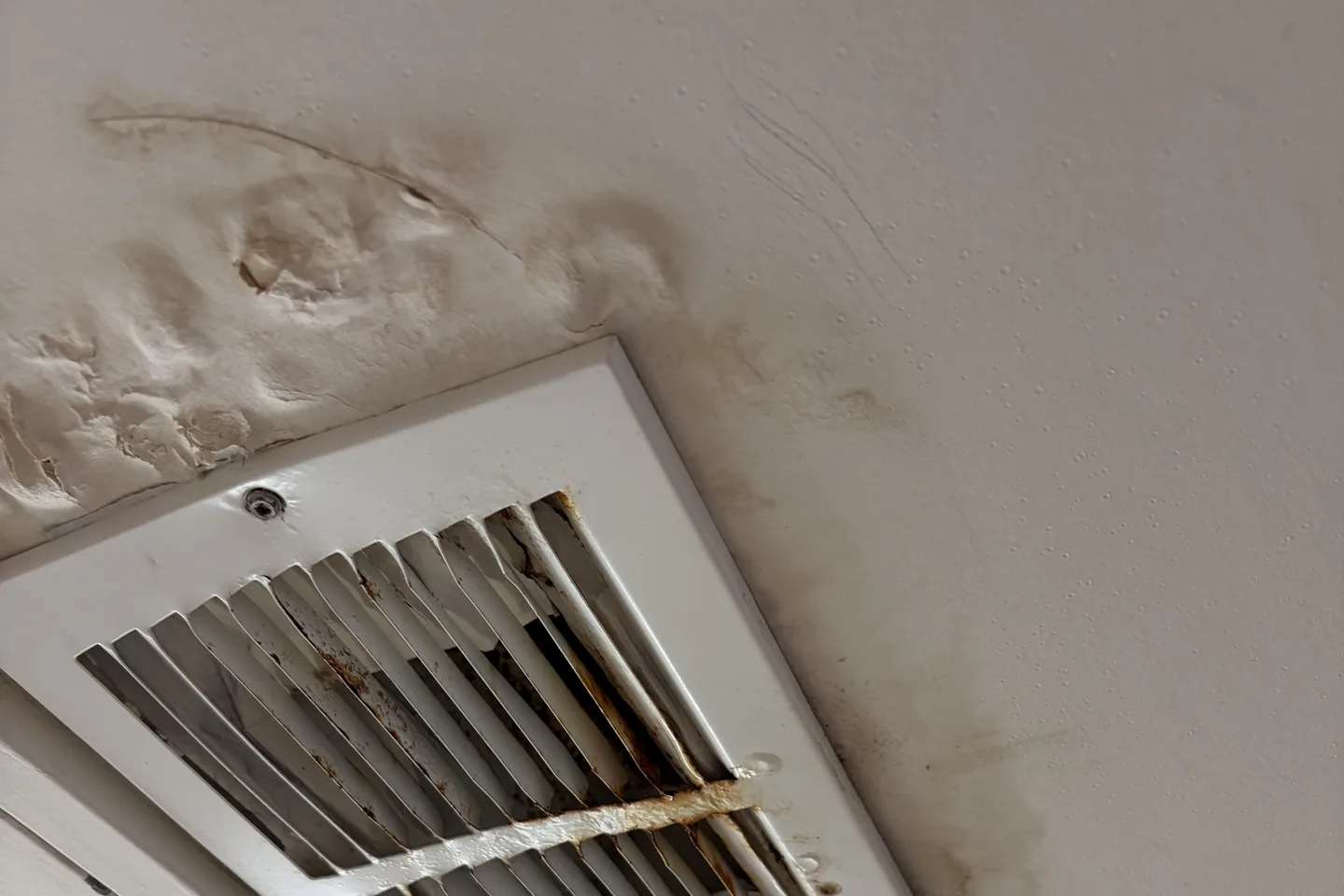 Water-damaged ceiling around an actively leaking HVAC supply register in a Dallas bathroom