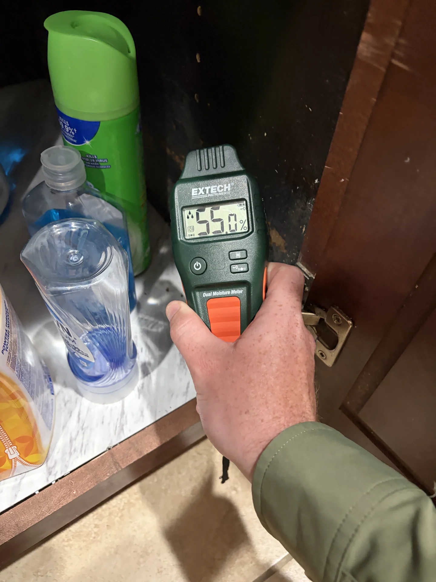 Comparative moisture reading beside visible cabinet discoloration