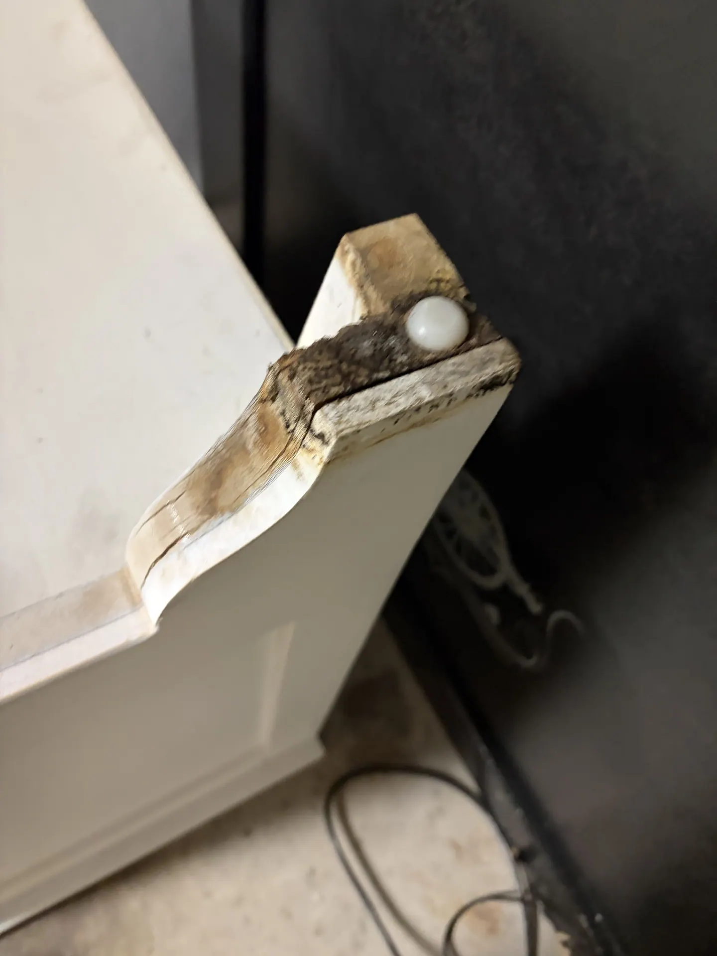 Visible dark growth and wood delamination on the foot and lower edge of a nightstand that stood on wet carpet