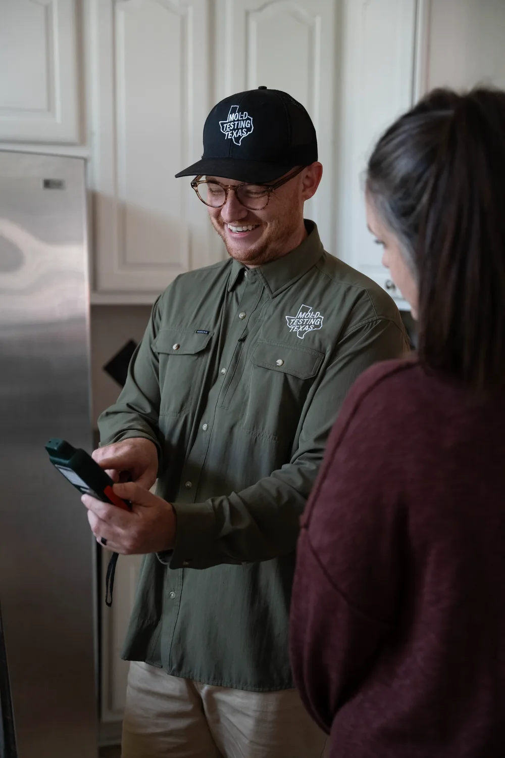 An inspector reviewing a moisture meter with a homeowner during an inspection